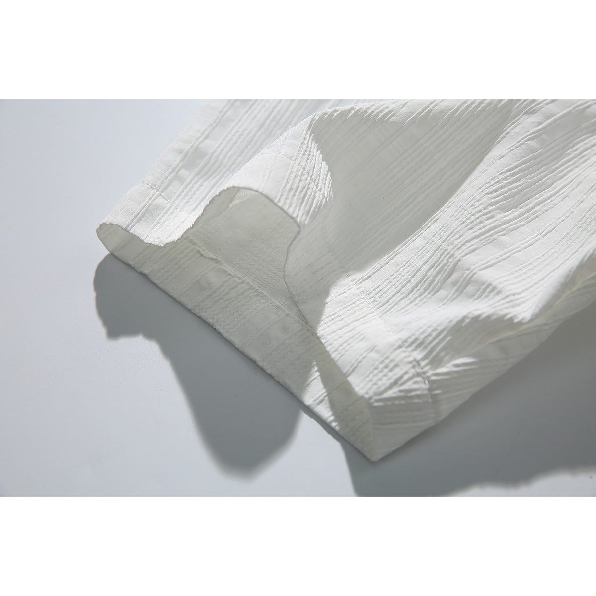 Close-up of the white shirt's short sleeve, showing its cuff seam and raised vertical stripe texture.