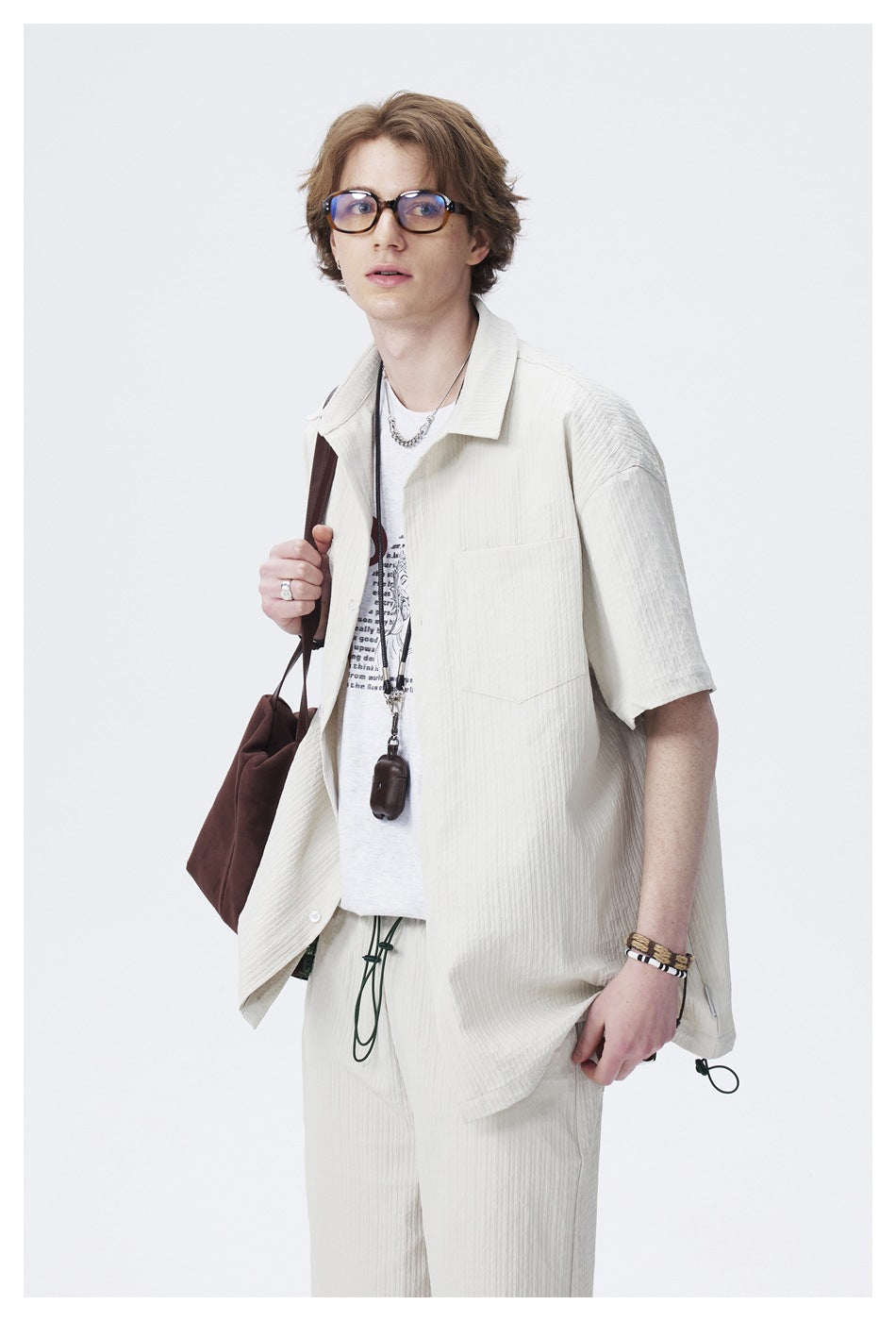 Closer view of a model wearing an off-white short-sleeve button-up shirt with a chest pocket over a graphic tee.