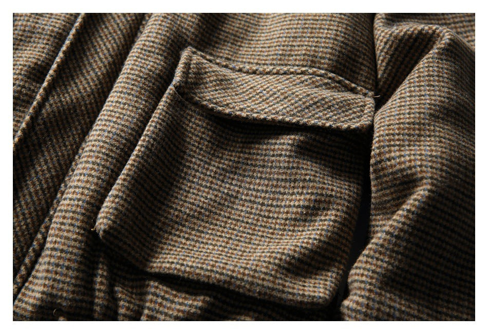 Close-up of a flap pocket on a brown, tan, and blue checked coat.