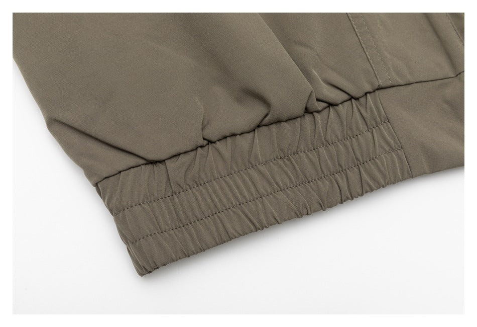 Close-up of the taupe jacket's gathered elastic hem band and stitching.