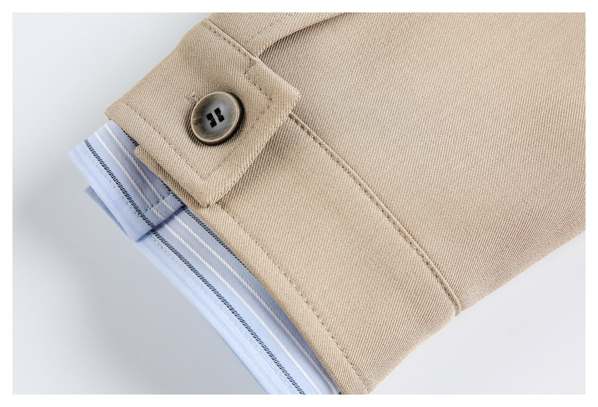 Close-up of a beige button tab beside light blue fabric with narrow dark and white stripes.