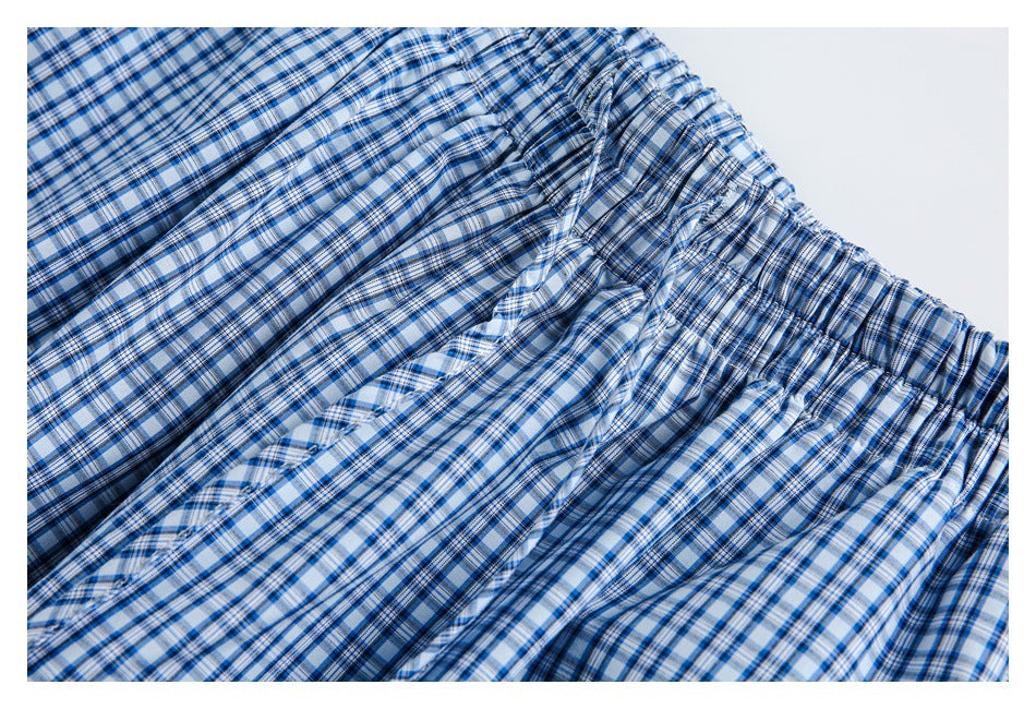 Close-up detail of blue-and-white checked pants showing gathered fabric and a stitched seam.