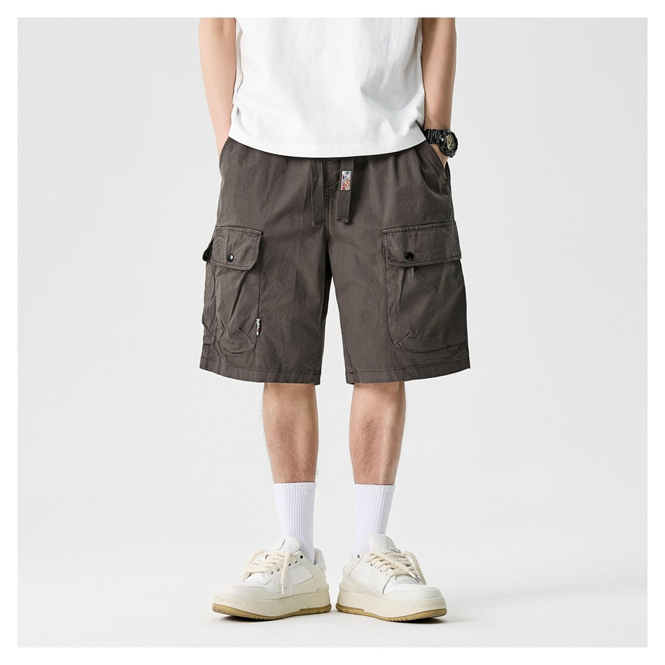 Cropped model wearing charcoal gray cargo shorts with large button-flap pockets, shown from the front.
