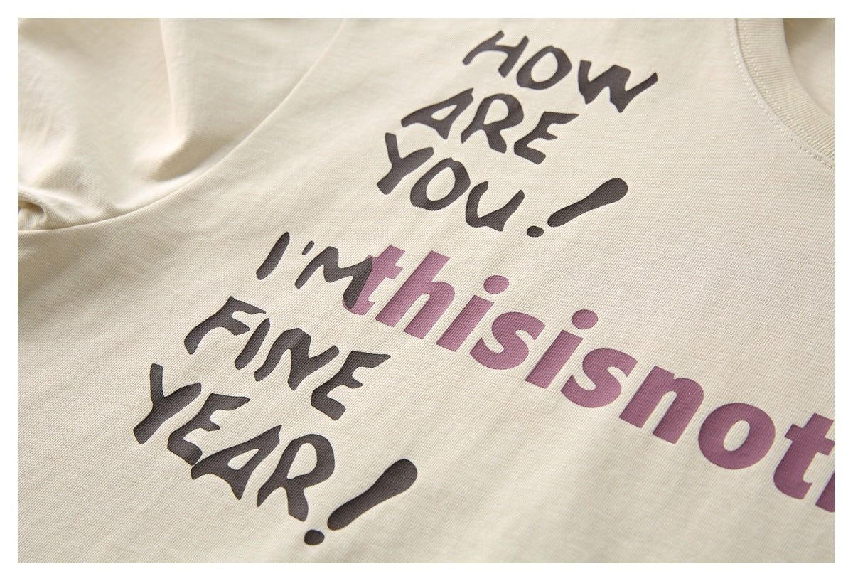 Close-up of a cream shirt with bold black and mauve English lettering printed across the fabric.