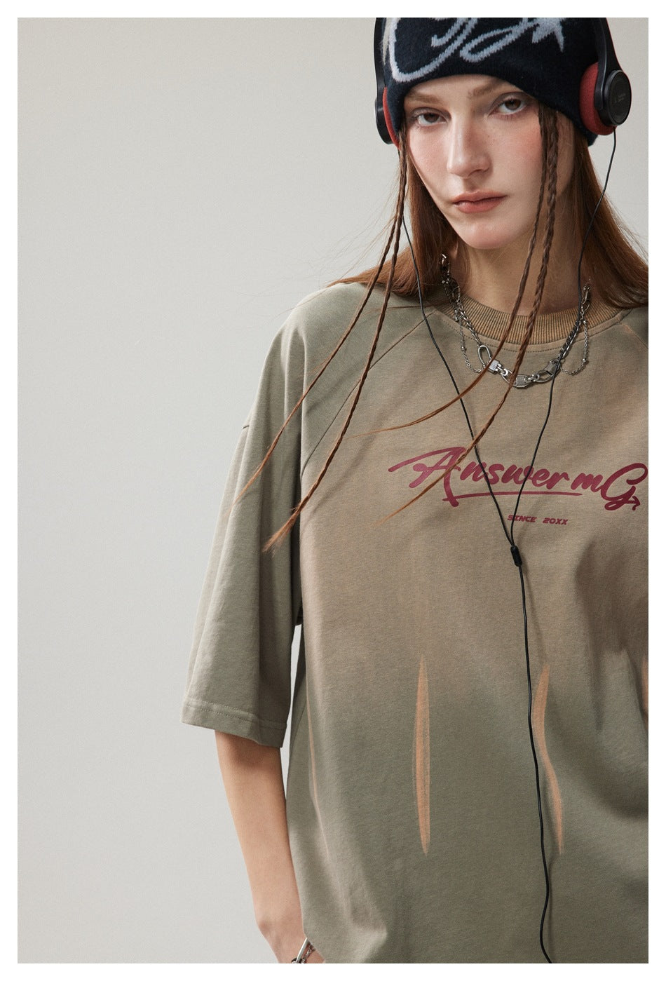Model in olive green oversized short-sleeve T-shirt with script print and streak details, cropped three-quarter view