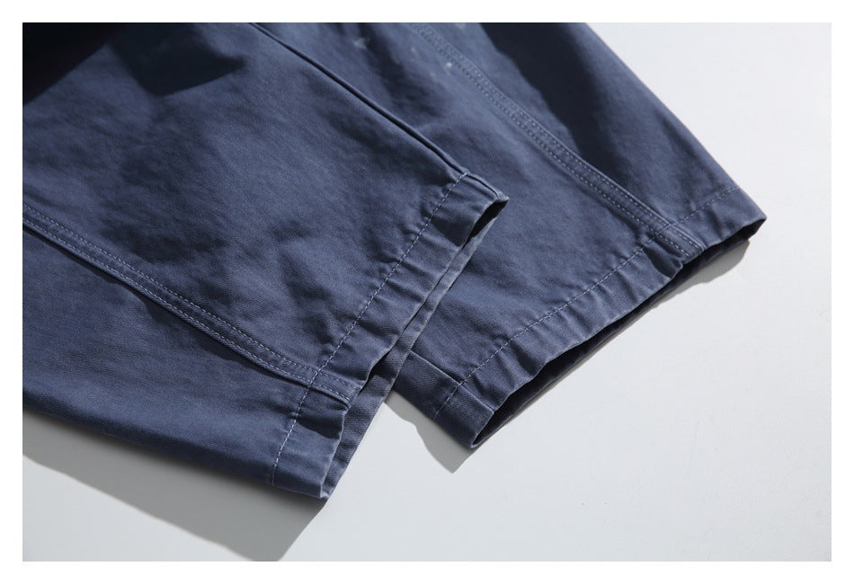 Close-up of the stitched hems on dark navy trousers laid flat.