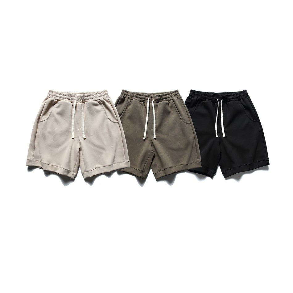 Three pairs of shorts shown from the front in light beige, taupe, and black, each with drawstrings and side pockets.