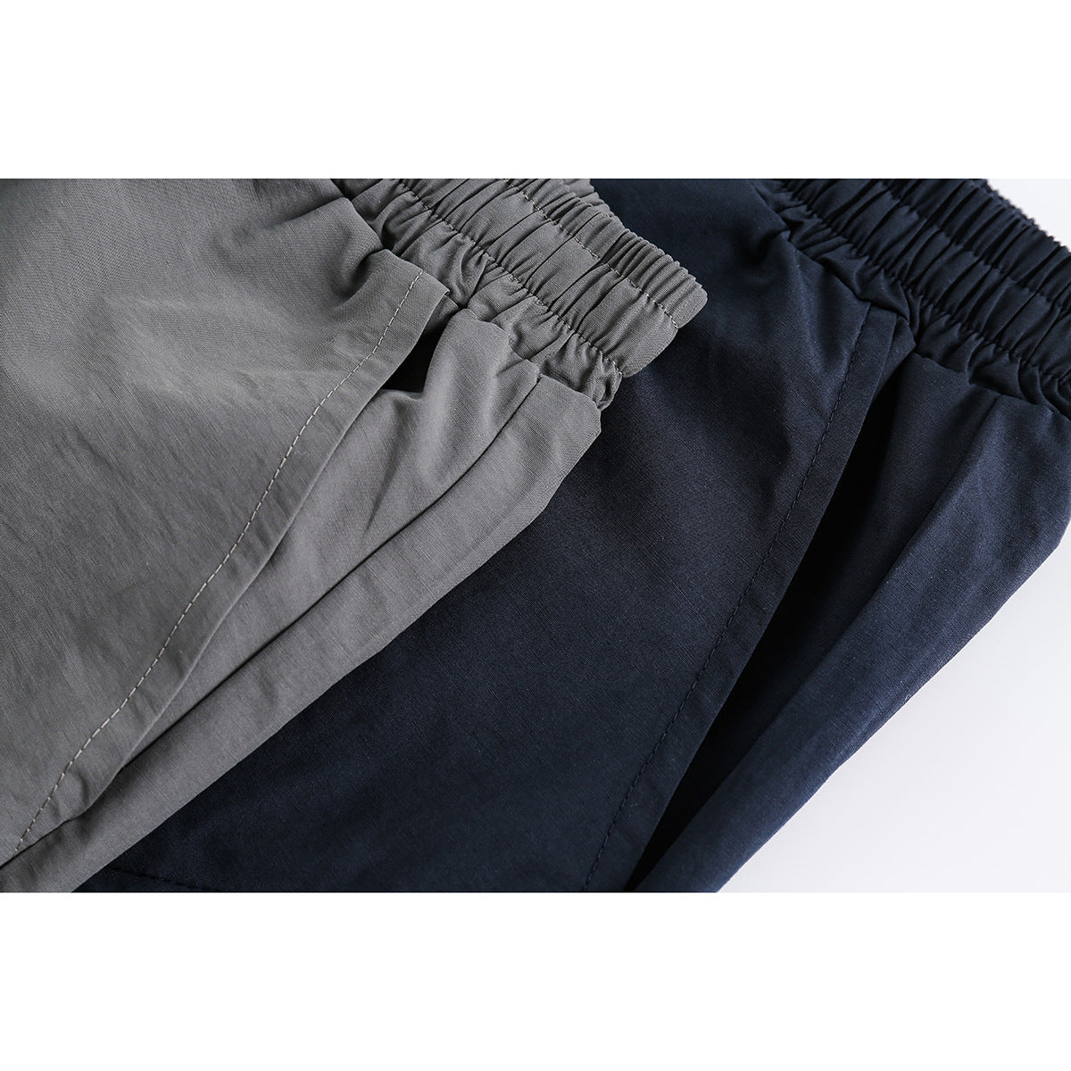 Close-up of gray and navy shorts showing the elastic waistbands, seams, and fabric.