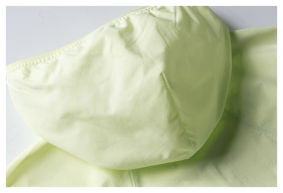 Close-up of a pale lime garment panel with curved seams and stitching.