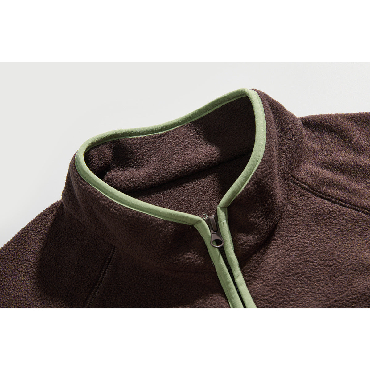 Close-up of a dark brown fleece jacket collar with a front zipper and pale green trim.