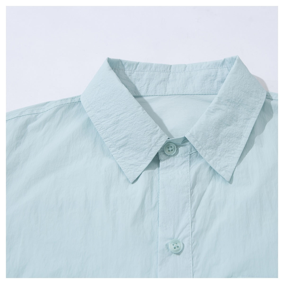 Close-up of a pale aqua button-up shirt’s pointed collar and front placket.