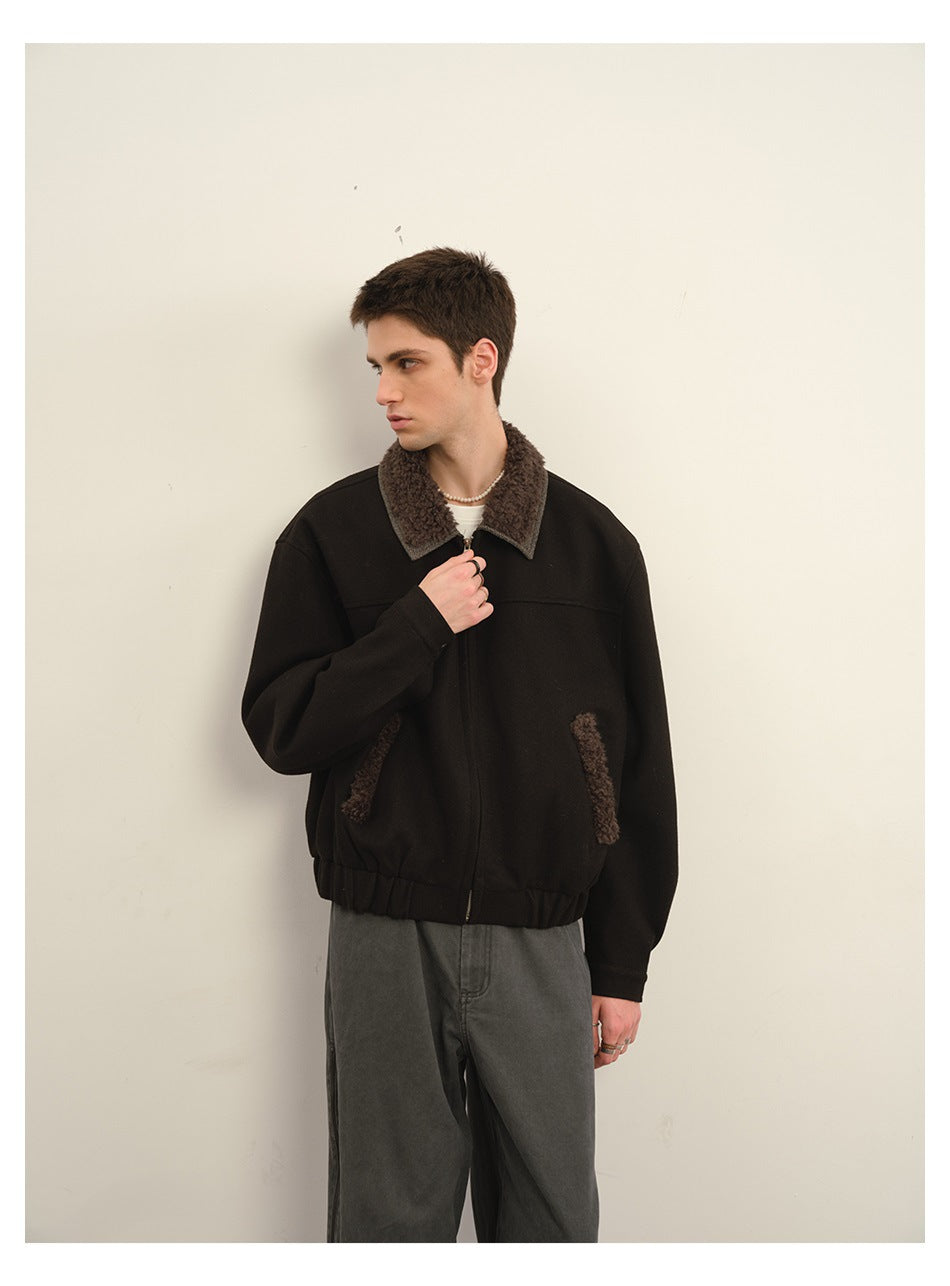 Model wearing a black zip jacket with a brown textured collar and pocket trim, shown from the front.
