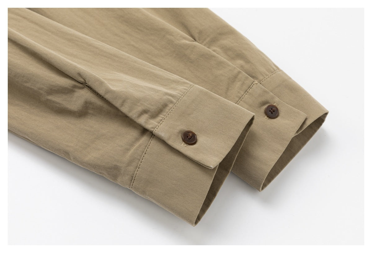 Close-up of two khaki shirt sleeve cuffs, each fastened with a dark button.
