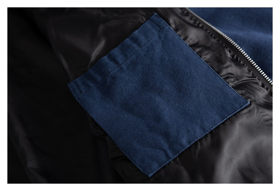 Inside view of a navy jacket showing a rectangular blue pocket against black lining beside the zipper.