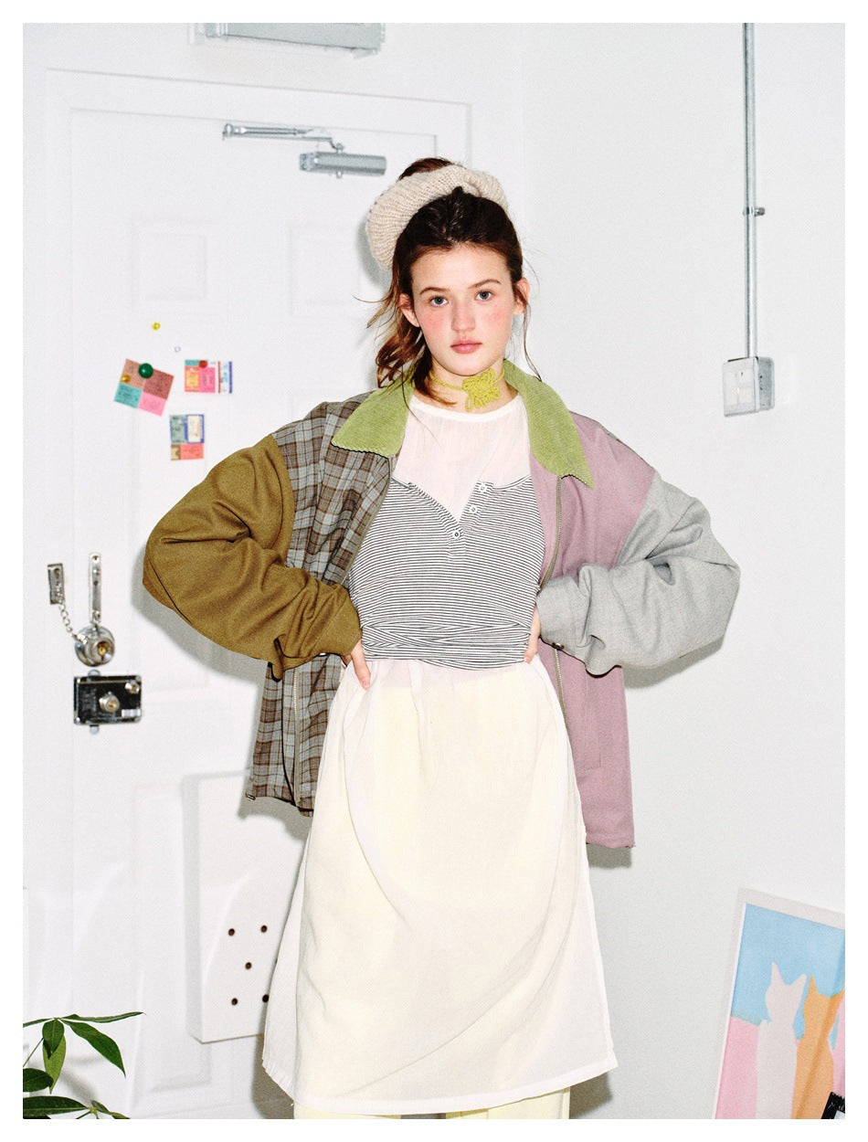 Model with hands on hips wearing color-block jacket with green collar over striped top and cream dress