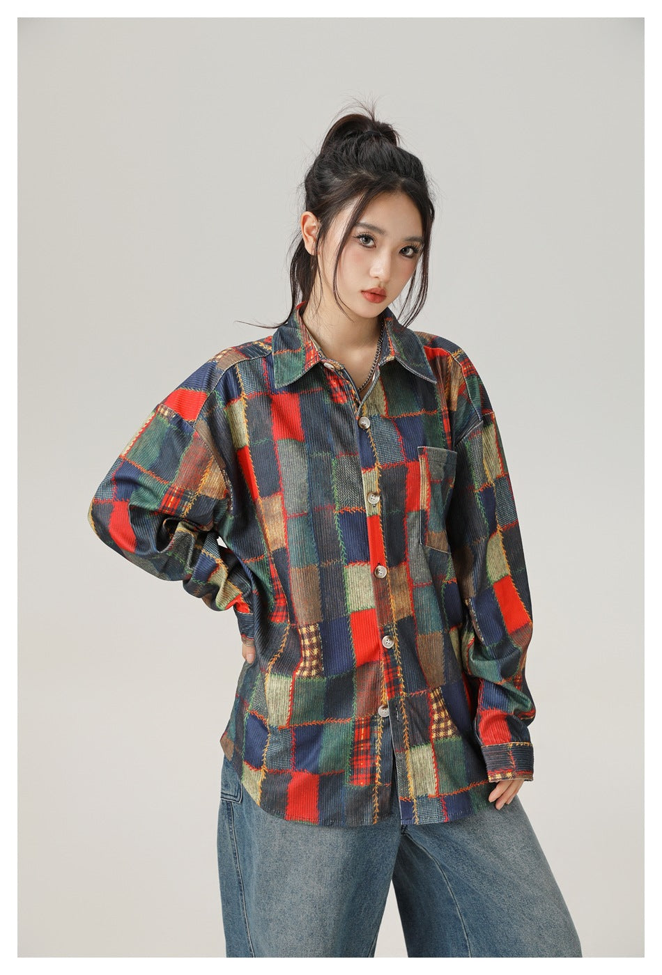 Closer view of a model wearing a button-front patchwork shirt with a chest pocket and wide-leg jeans.
