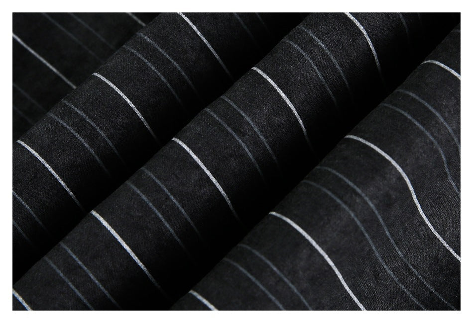 Macro view of black fabric with thin white pinstripes arranged across soft folds.