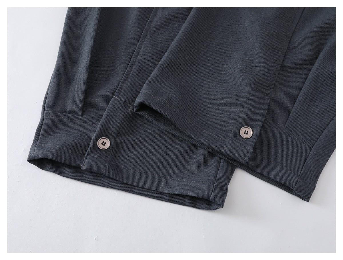 Close-up of charcoal trouser hems with adjustable button tabs.