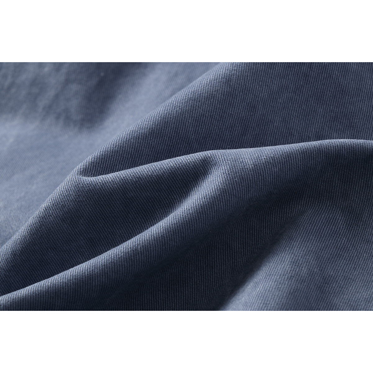 Macro view of the blue-gray trouser fabric, showing its fine diagonal weave and folds.