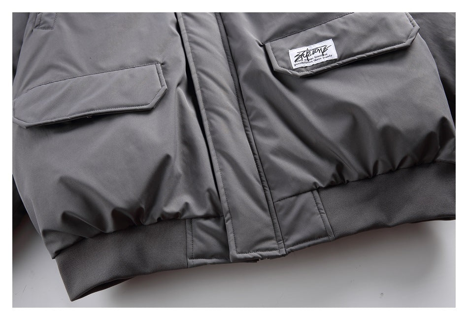 Close-up of the charcoal-gray jacket's front flap pockets and ribbed hem.