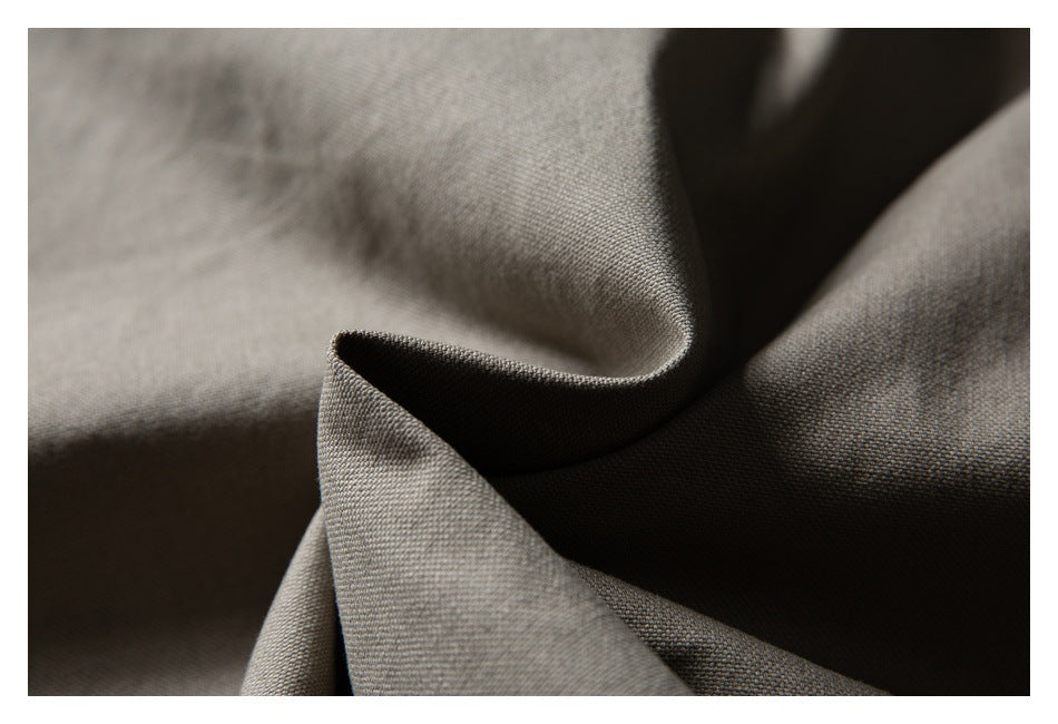 Close-up of taupe woven fabric draped into soft folds, showing its fine texture.