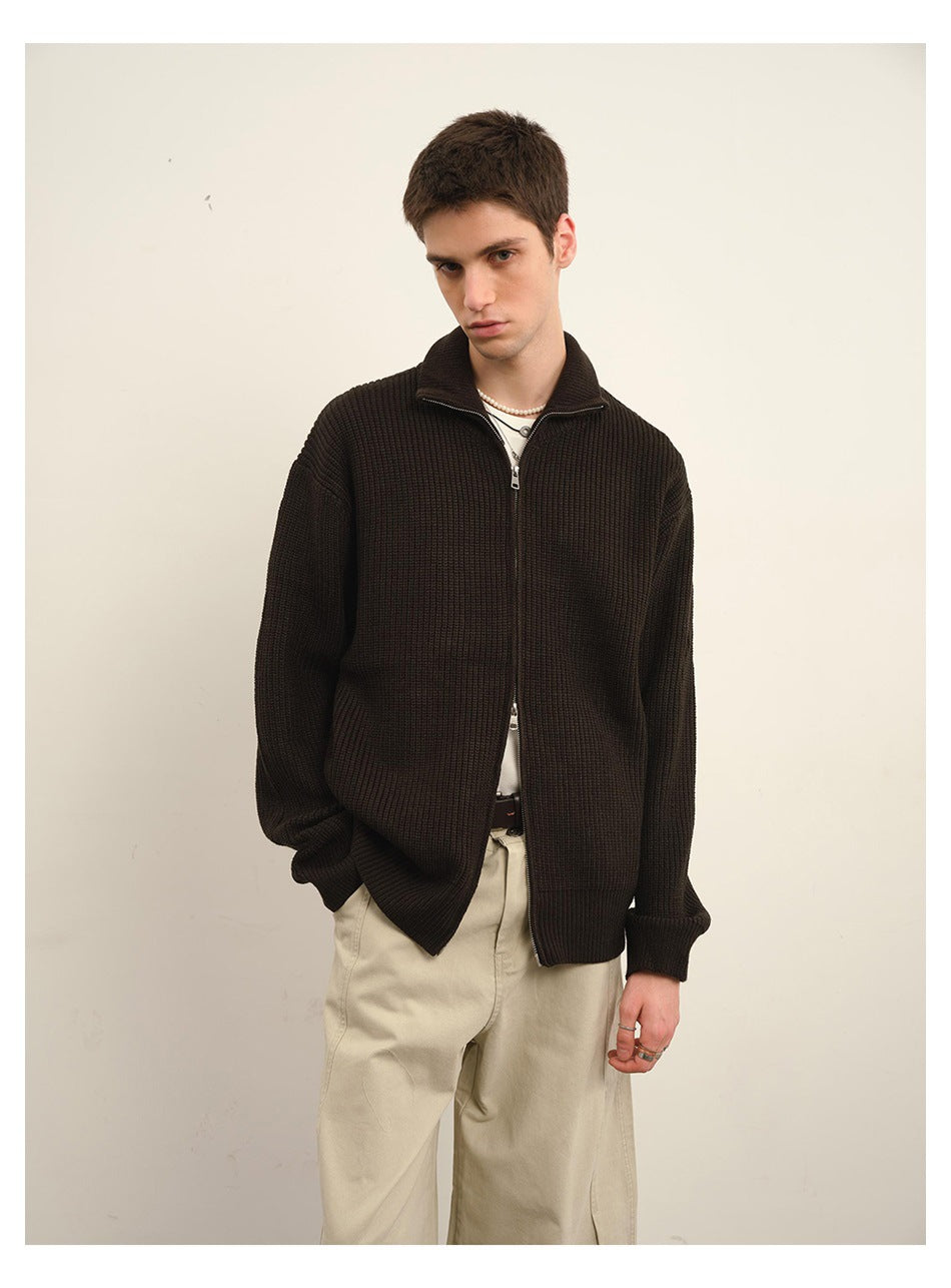 Man wearing a dark brown rib-knit zip cardigan with beige wide pants, front view with hand in pocket