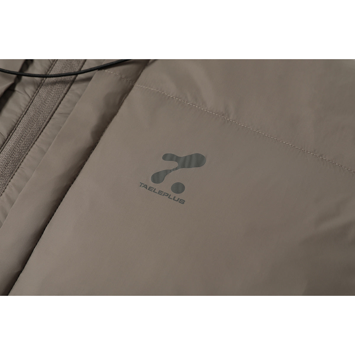 Close-up of a small dark logo printed on the taupe jacket chest.