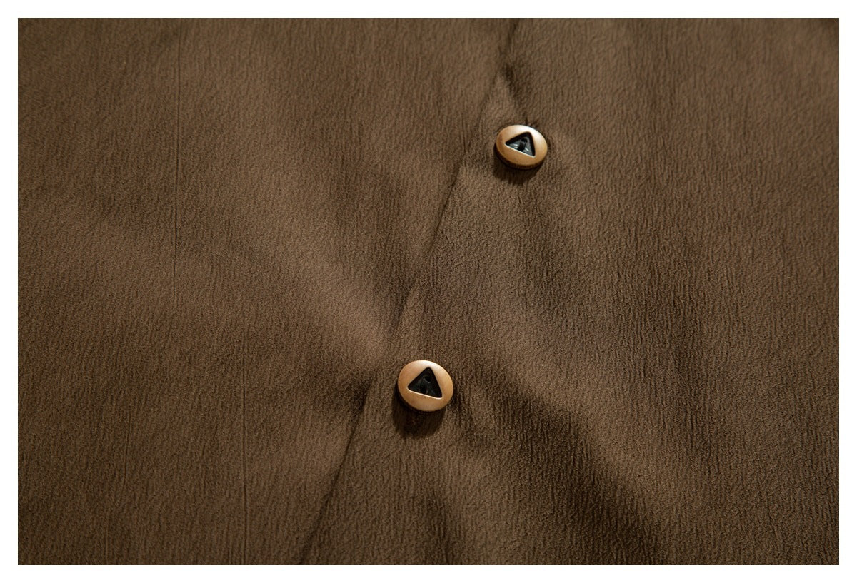 Close-up of the brown shirt's front placket with two tan buttons and dark triangular centers.