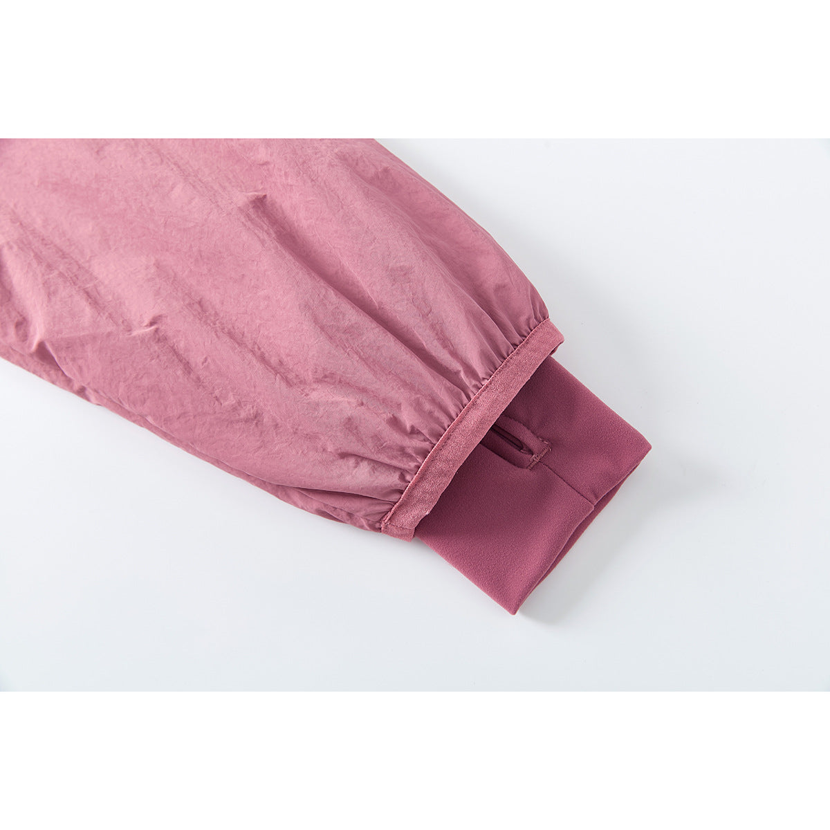 Close-up of a pink jacket sleeve cuff with a darker inner cuff and small fastening tab.