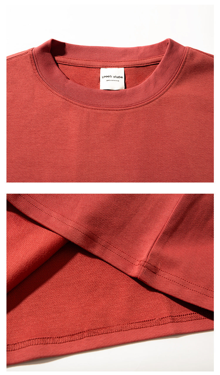 Close-up of the rust-red T-shirt's ribbed crew neck, sewn-in label and stitching, with a view of the hem.