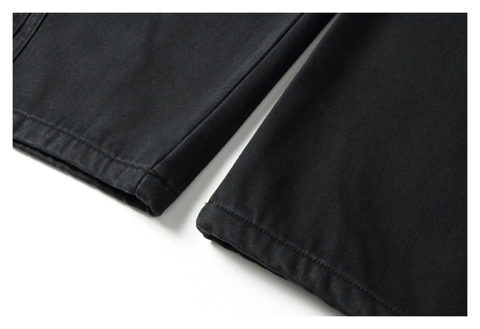 Close-up of the straight stitched hems on the legs of black pants.