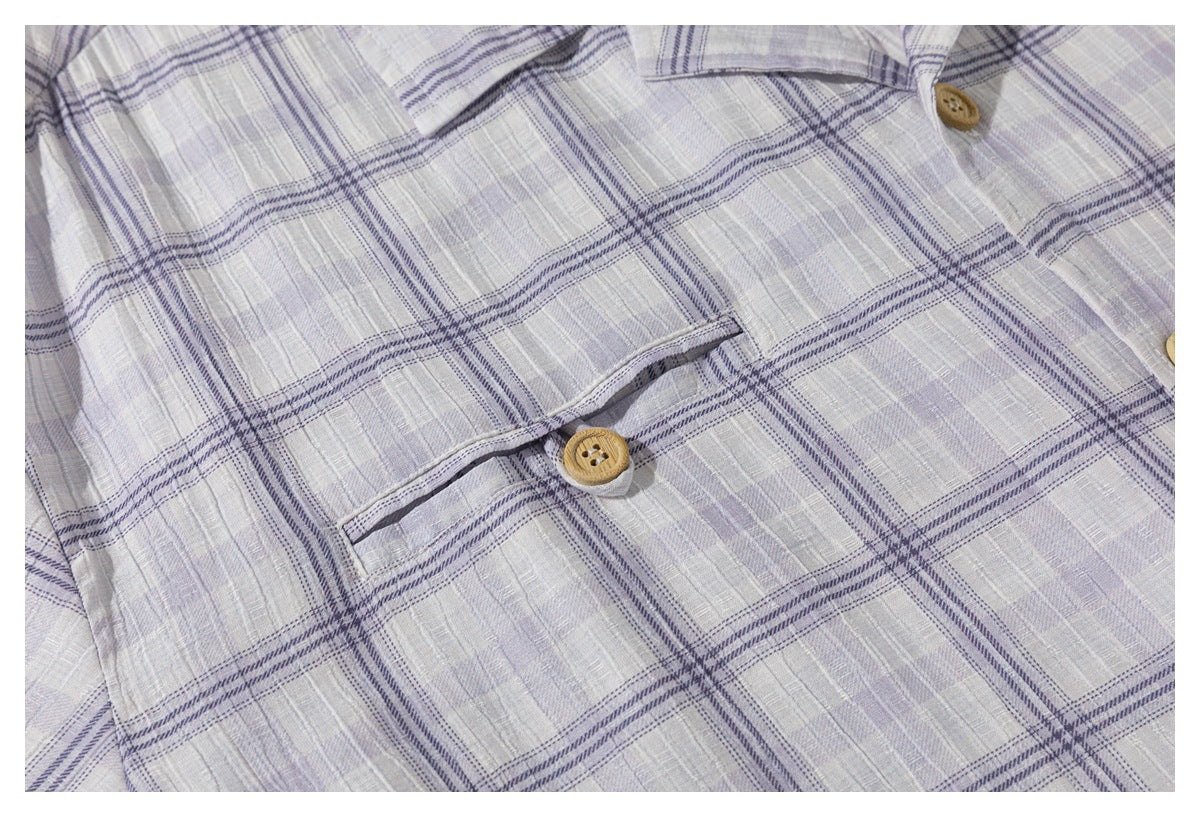 Close-up of the light gray-lavender plaid shirt's button-front pocket and tan buttons.