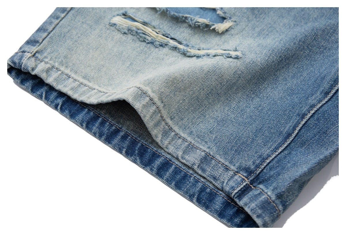 Close-up of the folded hem and leg opening of blue distressed jeans.