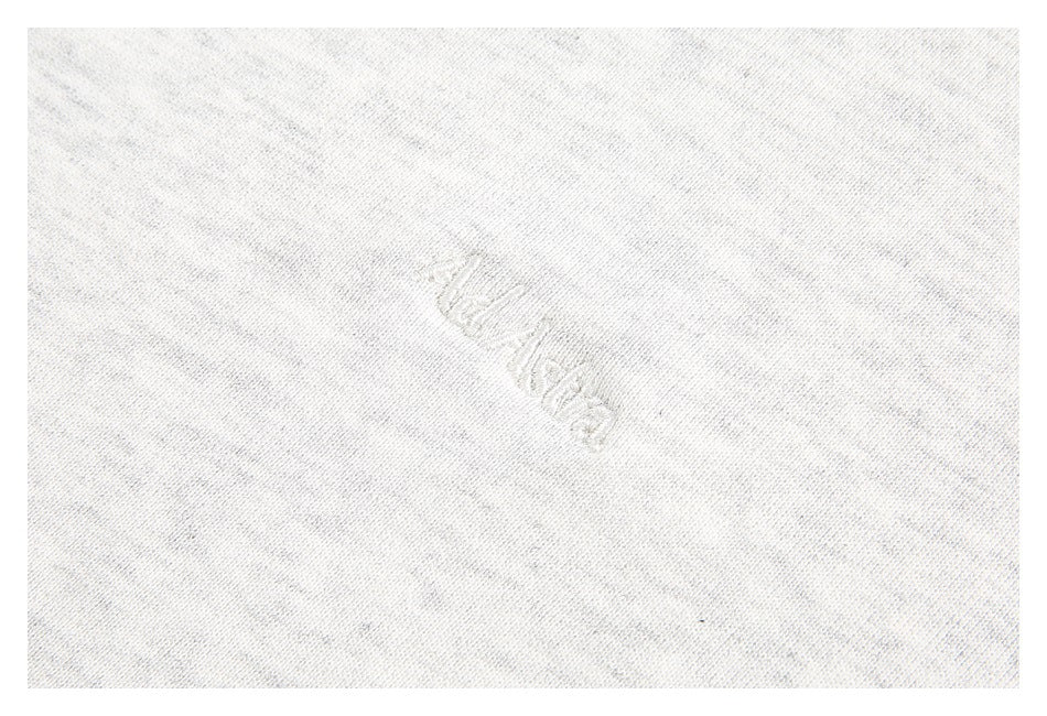 Close-up of faint tonal script embroidery on light gray sweatshirt fabric.