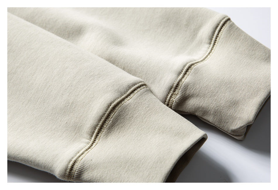 Close-up of two light beige sweatshirt sleeve cuffs with ribbing and stitched seams.