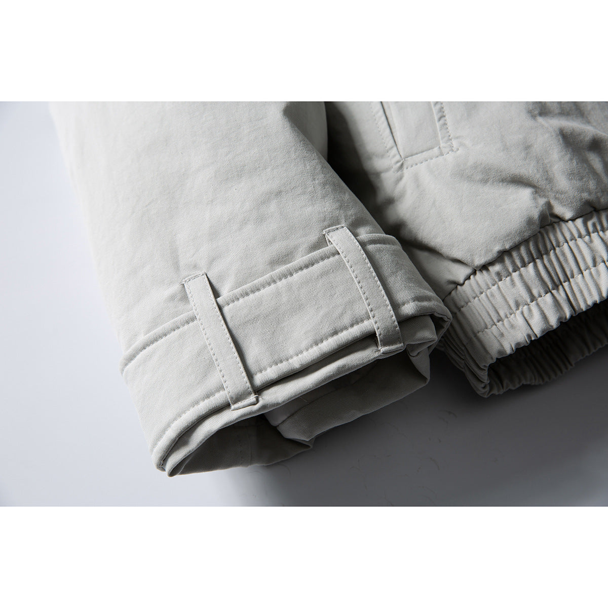 Close-up of a light gray jacket sleeve cuff with adjustment tabs beside the elasticized hem.