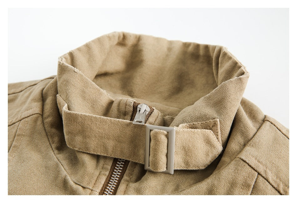 Close-up of a tan jacket's high collar, adjustable strap and metal buckle above the front zipper.