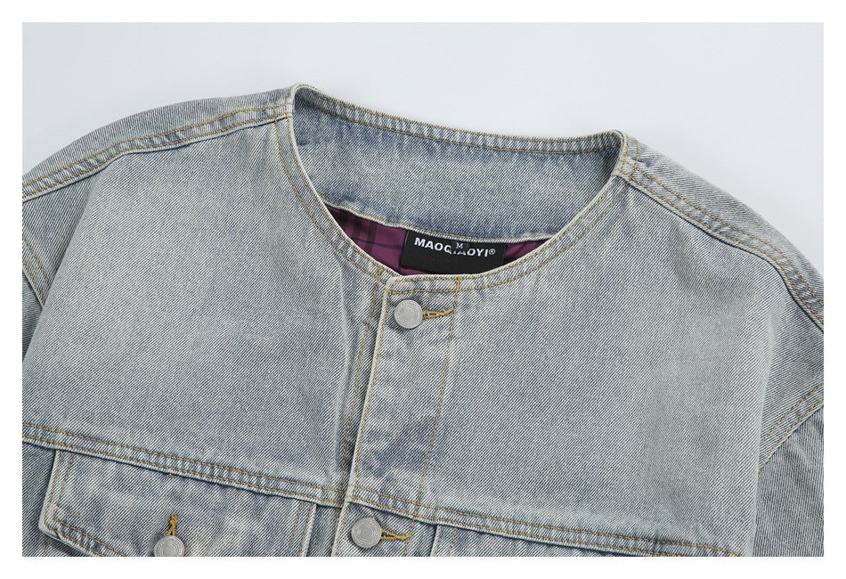 Close-up of a light-wash denim jacket neckline, metal buttons, and front yoke seams.