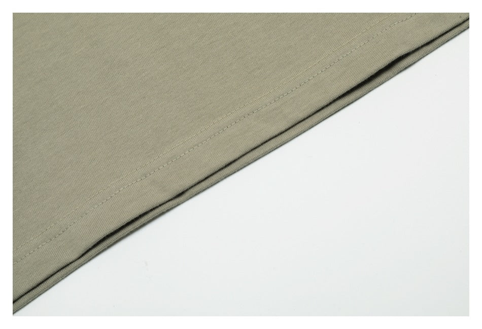 Close-up of the stitched lower hem on a muted gray-green T-shirt.