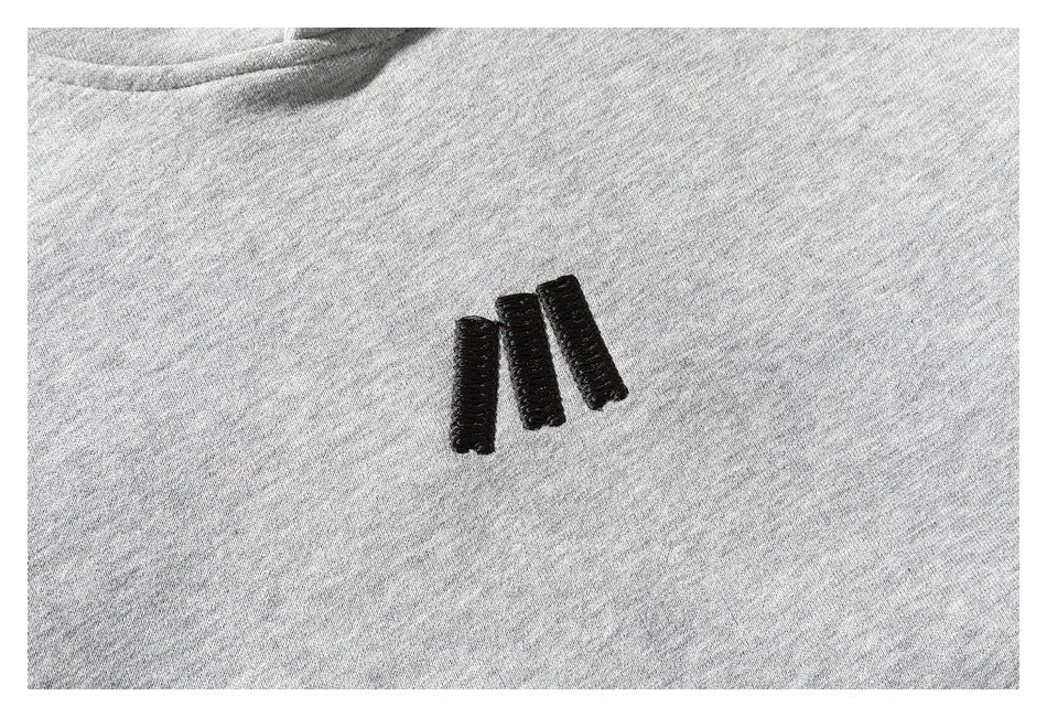 Close-up of a small black embroidered emblem on light gray sweatshirt fabric.
