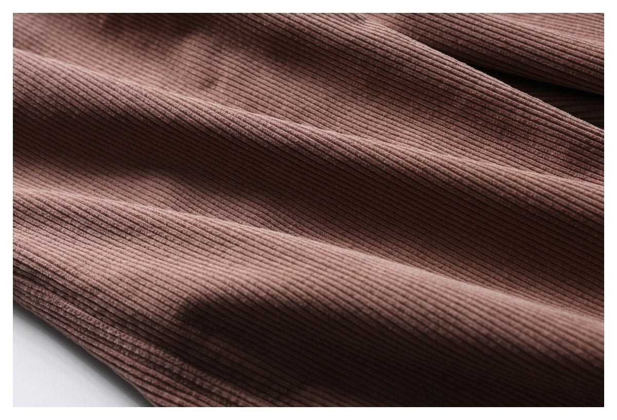Close-up of dusty rose ribbed trouser fabric arranged in soft folds.