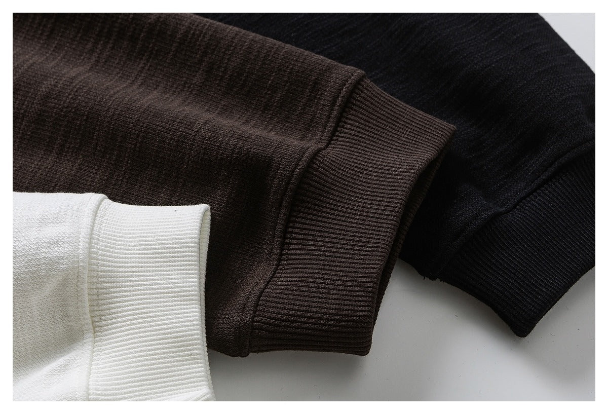 Close-up of ribbed sweatshirt cuffs in dark brown, black, and off-white.