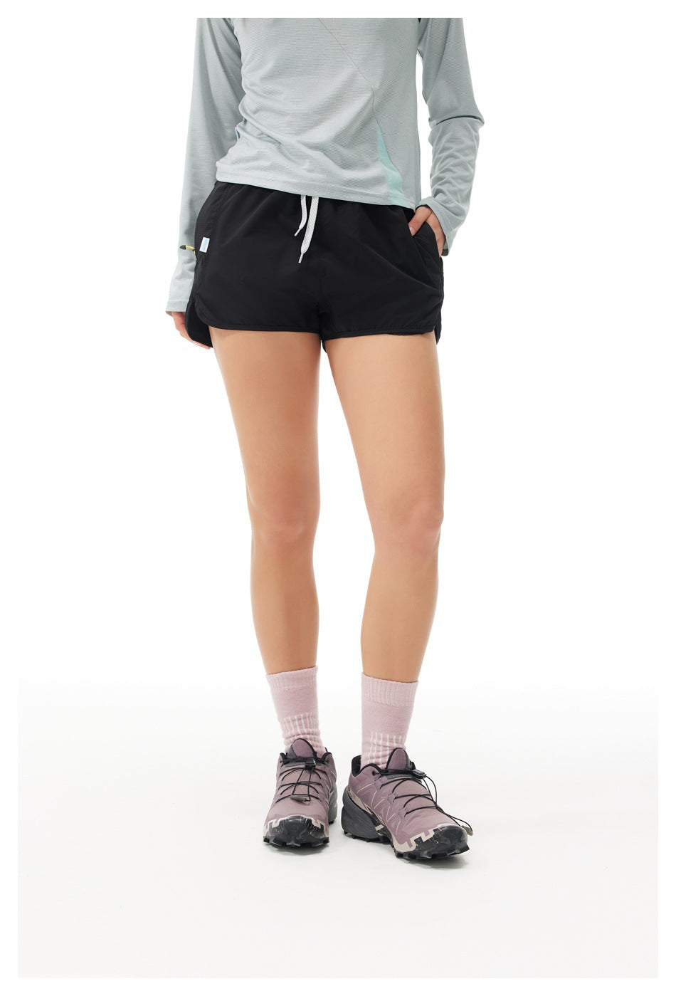 Front view of a model wearing black running shorts with a white drawstring and curved hems.