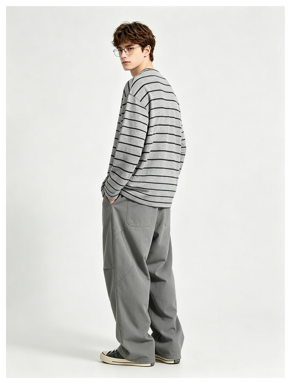 Model in the gray striped long-sleeve top with gray wide-leg pants, turned and looking back over his shoulder