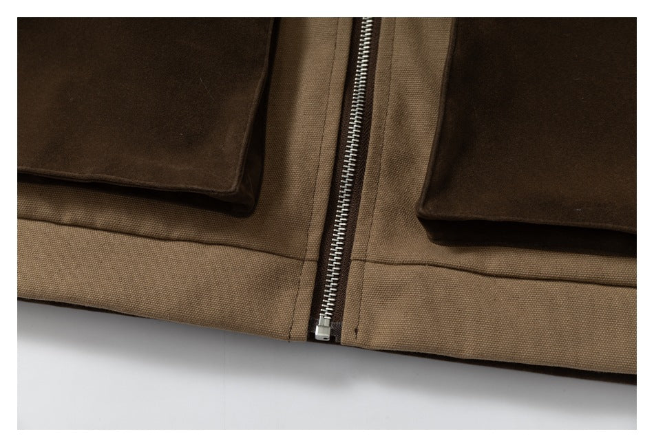 Close-up of a metal front zipper between tan fabric panels and dark brown pocket flaps.