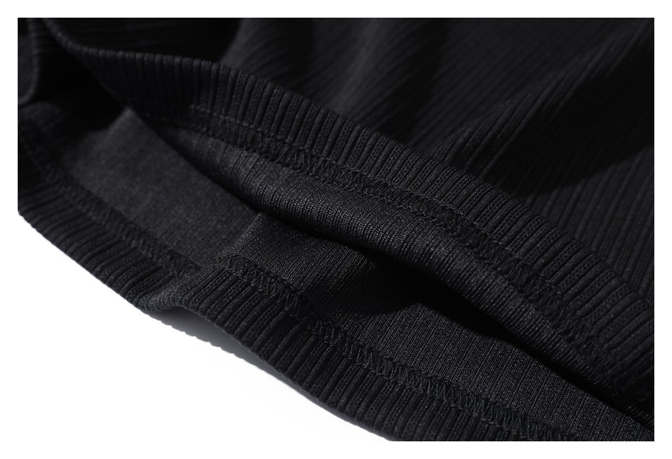 Close-up of the black ribbed garment's stitched inner seam and folded edge.