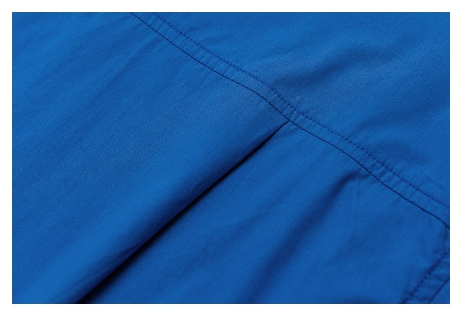 Close-up of overlapping bright blue garment panels and a diagonal double-stitched seam.