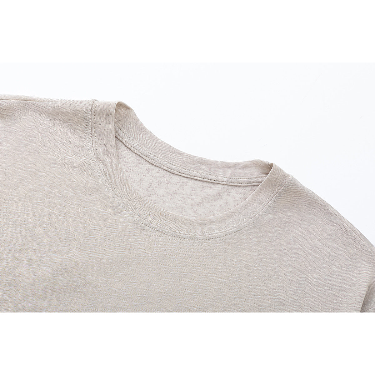Close-up of a light beige shirt's crew neckline, collar stitching, and shoulder.