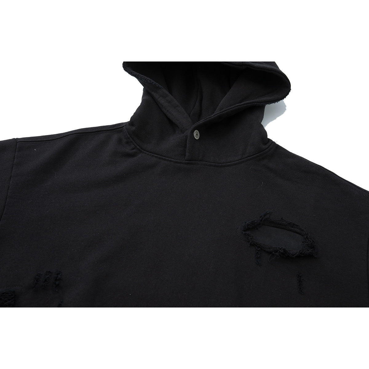 Close-up of a black hooded pullover with a snap at the neck and distressed patches on the front.