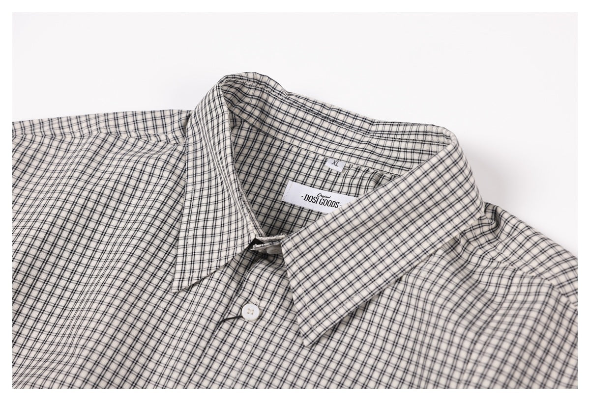 Close-up of a white shirt's black checked pointed collar, front button, and sewn-in neck label.